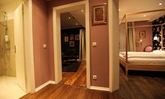 A spacious hallway with an open access to a bedroom and a bathroom. The walls are painted in soft colors, and there are stylish artworks.