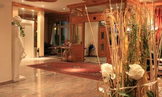 An elegant hotel lobby with stylish decor. There is a statue, flower arrangements, and an inviting atmosphere.