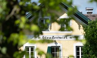 A charming building with a yellow facade and green shutters. The inscription "Strasserwirt" is clearly visible.