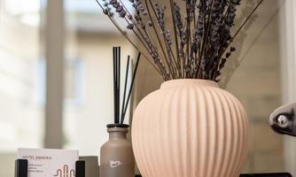 An elegant vase with lavender is placed in a stylish room. Next to it stands a decorative bottle and an information card about the hotel.