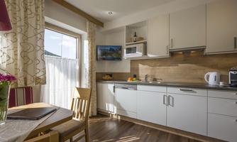 A modern kitchen with bright cabinets and a table. Natural light streams in through the window.