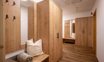 A modern changing room with wooden lockers and a bright, friendly atmosphere. There are benches and mirrors for the users.