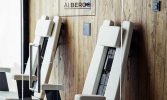 Two modern, comfortable chairs stand against a wooden wall. In the background, a sign reading "ALBERGO" can be seen.