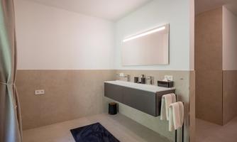 A modern bathroom with an elegant sink and a large mirror. The walls are light and designed in a minimalist style.