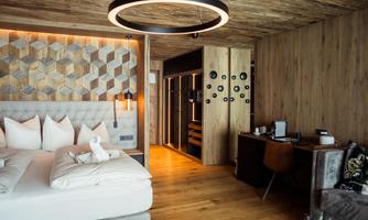 A modern hotel room with wooden walls and a stylish design. The room features a large bed and a workspace.