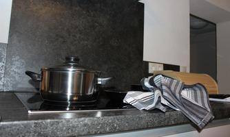 A modern kitchen with a pot on the stove and a dish towel. The space is in neutral tones.