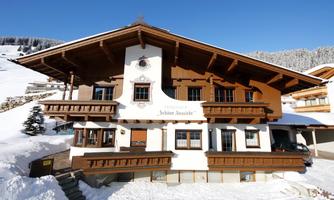 A picturesque chalet in the snow with traditional wooden architecture. The surroundings are surrounded by snowy mountains.