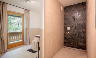 A modern bathroom with an elegant shower and stylish towels. In the background, a window is visible, offering a view of the greenery.