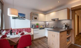 A modern kitchen with bright furniture and a cozy dining area. The layout is open and inviting, perfect for social gatherings.