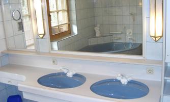 A modern bathroom with two sinks in blue. In the background, a bathtub and a window are visible.