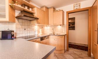 A modern kitchen with wooden cabinets and a bright countertop. The space is well-lit and has a cozy character.