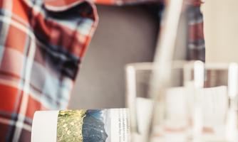 A striped shirt lies on a chair, while a paper with a landscape image and text on it is visible. In the background, glasses stand that are slightly blurred.