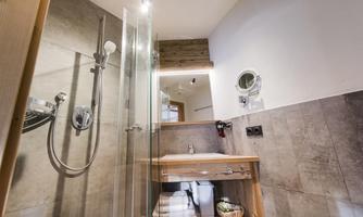 A modern bathroom with a glass shower and wooden details. The clean and bright environment creates a relaxing atmosphere.