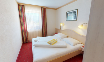 A cozy hotel room with two beds and fresh towels.  
Large windows let in plenty of light and create an inviting atmosphere.