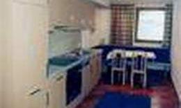 A small kitchen with a dining table and chairs. The walls are light and a window provides natural light.