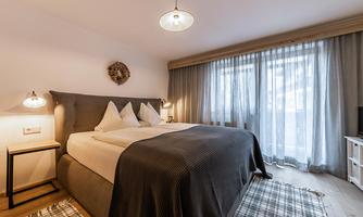 A modern bedroom with a large bed and bright curtains. The room is designed to be friendly and inviting.