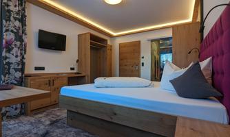 A cozy bedroom with modern wooden furniture. The lighting creates an inviting atmosphere.