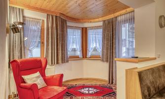 A cozy living area with a red armchair and carpet. The large windows let in plenty of light and create an inviting atmosphere.