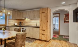 A modern kitchen with wooden furniture and an open design. The dining area is bright and inviting, ideal for sociable meals.