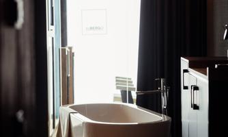 A modern bathroom with a freestanding bathtub. Large windows and an elegant ambiance characterize the space.