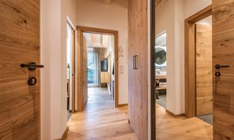 A bright hallway with wooden doors and a warm wooden floor. The space conveys an inviting and modern atmosphere.