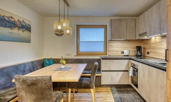 A modern kitchen with a dining table and beautiful pendant lights. The furniture is made of light wood, and there is a cozy atmosphere.