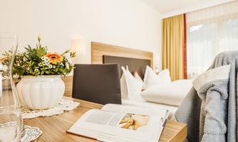 A cozy room with a modern decor. On the table lies a book and a vase of flowers, which give the room an inviting atmosphere.