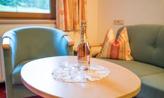 A cozy living area with two armchairs and a table. On the table, there is a bottle of champagne and two glasses.