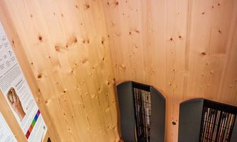 A modern sauna with walls made of light wood and a wooden bench. On the bench lie two white towels.
