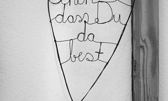 A decorative wire heart hangs on the wall. It reads in ornate script "Nice to have you here".