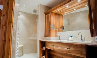 A modern bathroom with wood details and an elegant washbasin. The shower is open and designed in a modern style.