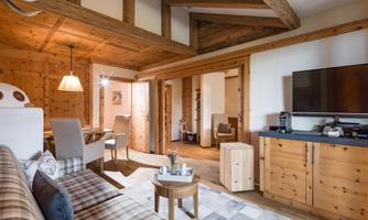 A cozy living room with wooden walls and a modern television. The decor is bright and inviting, perfect for relaxing hours.