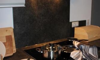 A modern kitchen with a stove and a pot on the cooktop. The room is well-lit and neatly furnished.