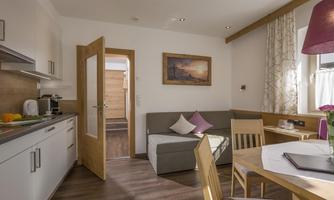 A cozy living kitchen with modern furniture. The room is bright and friendly, with a dining area and a sofa corner.
