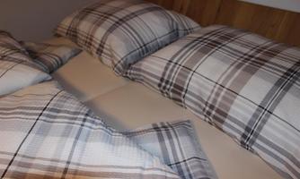 A cozy bed with checkered pillows and bedding. The decor exudes calm and comfort.