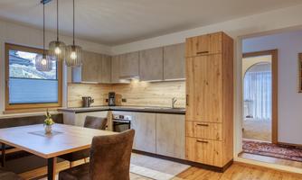 A modern kitchen with wooden cabinets and a dining table. The atmosphere is warm and inviting.