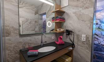 A modern bathroom with a sink, mirror, and several towels. The walls are decorated with elegant, light tiles.