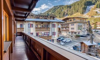 A balcony overlooking a charming alpine landscape. In the background, mountains and several buildings are visible.
