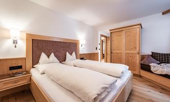 A cozy bedroom with two single beds and light wooden furniture. The atmosphere is warm and inviting, ideal for restful nights.