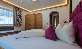 A modern bedroom with a comfortable bed and elegant pillows. The warm wood tones and soft lighting create an inviting atmosphere.
