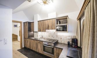 A modern kitchen with wooden furniture and shiny appliances. The space is bright and invitingly designed.