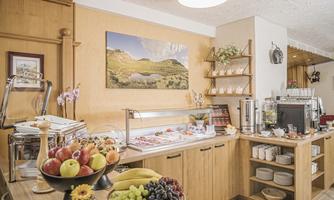 An inviting breakfast buffet with fresh fruit, bread, and various dishes. The room is bright and cheerfully designed.
