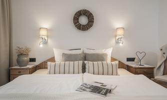 A cozy bedroom with a large bed and bright walls. The lighting creates an inviting atmosphere.