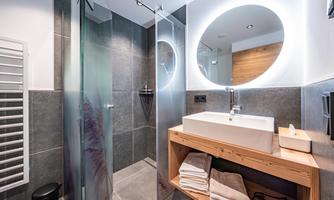 A modern bathroom with a glass shower and an elegant sink. Bright light accents and light tiles create an inviting atmosphere.