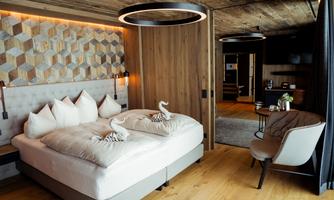 A modern bedroom with a large bed and elegant pillows.  
Wood details and soft lighting create a cozy atmosphere.