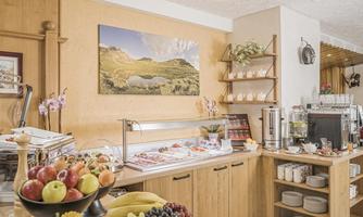 An inviting breakfast buffet with fresh fruit, cold cuts, and cheese. The wooden shelves and cozy decorations create a pleasant atmosphere.
