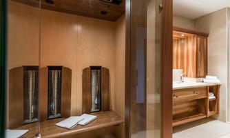 A modern wellness area with wooden elements and clean, bright surfaces. Comfortable benches and towels invite relaxation.