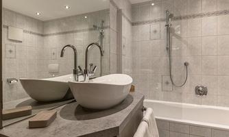 A modern bathroom with a freestanding bathtub and two sinks. Bright tiles and a large mirror wall create an inviting atmosphere.
