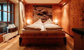 A cozy bedroom with wooden decor and a large bed. The warm lighting creates an inviting atmosphere.