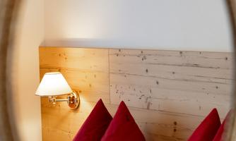 A cozy room with red cushions and warm wooden paneling. The light is softly illuminated by a wall lamp.